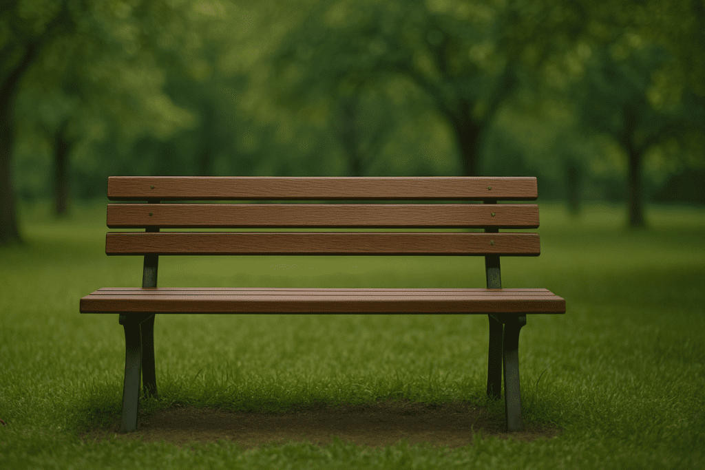 A wooden park bench sits on green grass beneath leafy trees, bathed in soft daylight with a blurred background creating a peaceful atmosphere.
