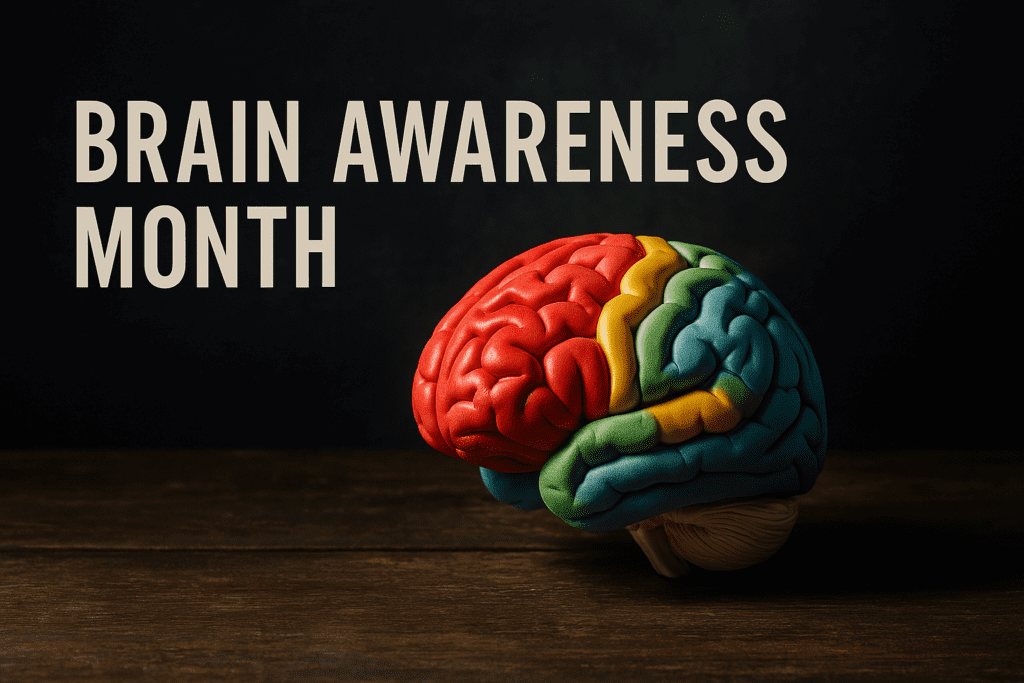 A photograph features an anatomically detailed, multicolored brain model placed on a rustic wooden table, dramatically lit from the side to emphasize texture and form. The moody shadows and dark backdrop highlight the symbolic significance of Alzheimer’s awareness and the visual impact of Brain Awareness Month education efforts.